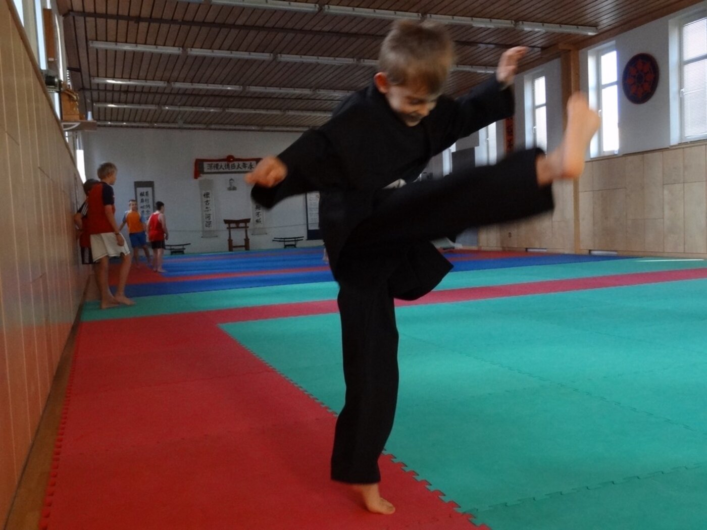 Child practising a martial-arts kick in a dojo – calm body, calm mind